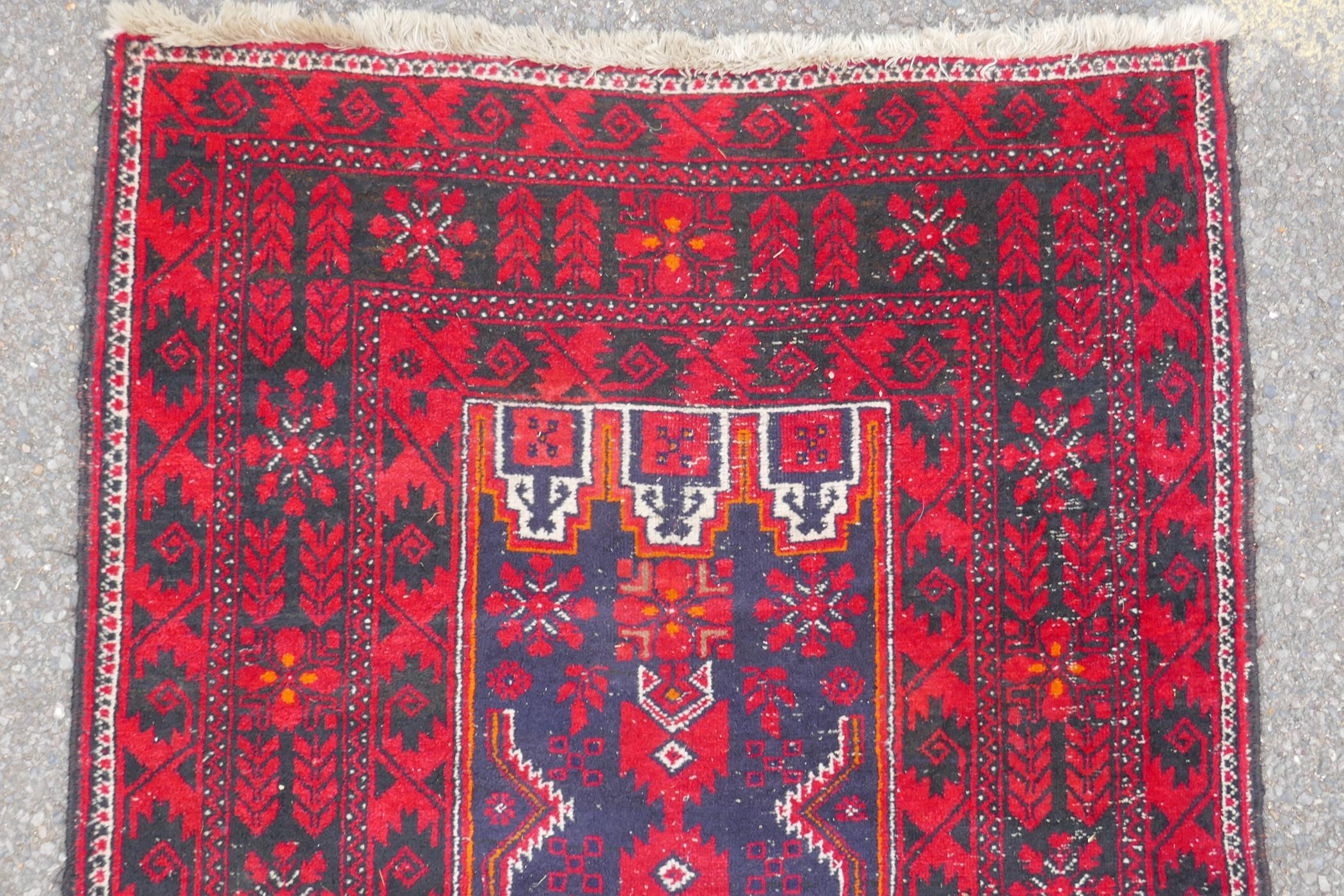 A Turkish deep red ground wool rug, with geometric designs on a central deep blue cartouche, 100 x - Image 5 of 7