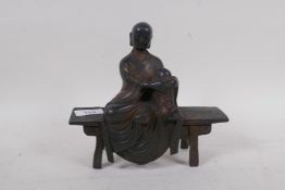 A bronze figure of a Buddha seated upon a bench with red and gilt patination, 18cm high