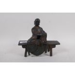 A bronze figure of a Buddha seated upon a bench with red and gilt patination, 18cm high