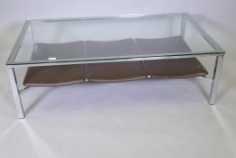 A glass top coffee table with chrome base and leatherette undertier, 120 x 70cms