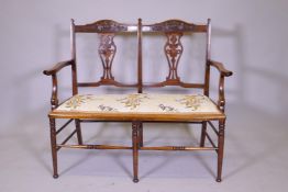 A Victorian beechwood two seater settee with carved and pierced back, raised on turned supports,