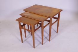 A mid century teak nest of three occasional tables, raised on tapering supports, 59cm x 39cm x 48cm