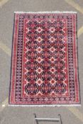 A Persian wool rug with Bokhara style medallion design and blue borders, 125cm x 180cm