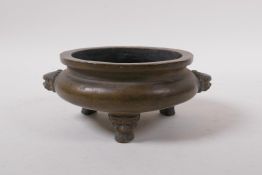 An antique bronze censer with two lion mask handles and tripod feet, impressed seal mark to base,