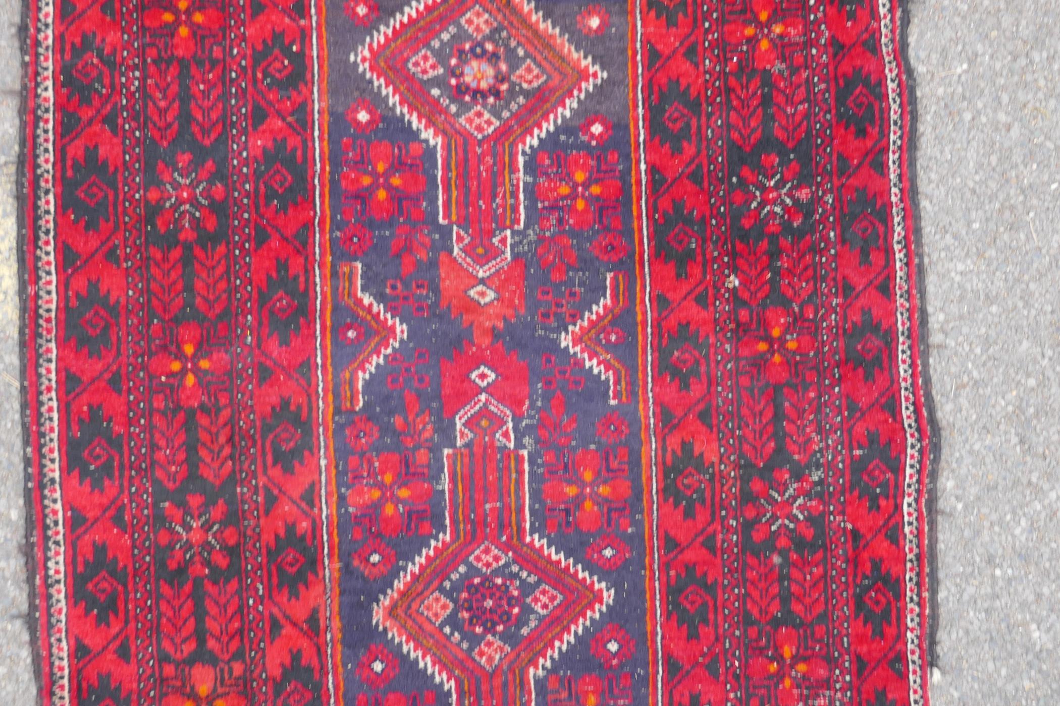 A Turkish deep red ground wool rug, with geometric designs on a central deep blue cartouche, 100 x - Image 3 of 7