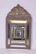 A C19th French cushion wall mirror with repousse brass plate decoration incorporating floral designs