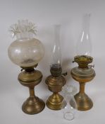 A near pair of brass column oil lamps and another similar, with one engraved shade and various