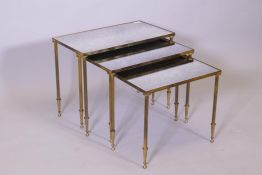 A nest of three Maison Junsen brass tables with antiqued mirrored glass tops, 56cm x 31cm, 49cm high