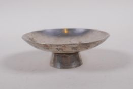 A Chinese white metal trinket dish with raised support and chased character inscription, 9cm