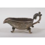 A Chinese white metal libation cup on tripod supports, with dragon head shaped handle and mythical