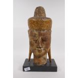 A carved giltwood head of Buddha, 43cm high