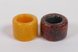 An amber hardstone archers thumb ring and a lacquer thumb ring, 4cm diameter