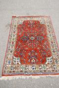 An eastern red ground hand woven wool carpet decorated with a multicolour flower and bird design,