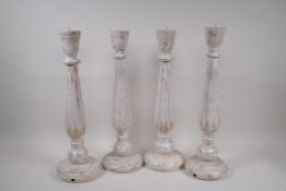 Two pairs of painted and distressed pricket candlesticks, 46cm high