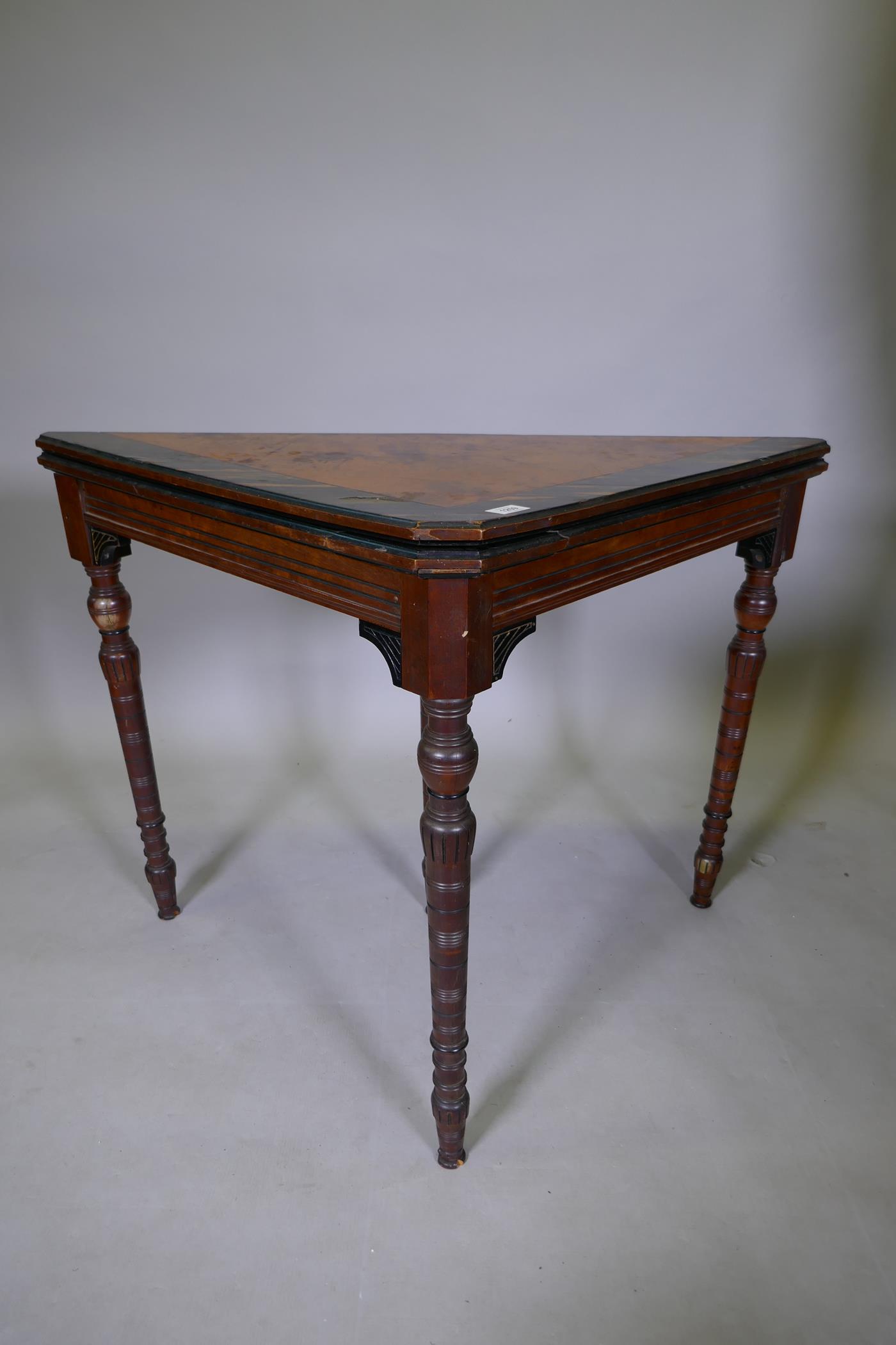 An Arts & Crafts satinwood and coromandel games table with fold over top and turned supports, 75 x