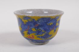 A Chinese crackleware tea bowl with blue, white and red dragon and phoenix decoration on a yellow