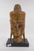 A carved giltwood head of Buddha, 43cm high