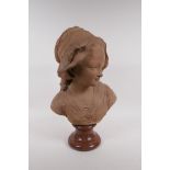 A C19th terracotta bust of a young girl in a bonnet, mounted on a marble socle, 46cm high