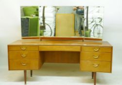 A 1970s Meredew teak dressing table and stool, with triptych mirror and seven drawers, 163 x