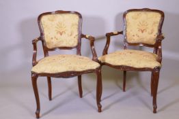 A pair of French style stained beechwood elbow chairs with carved decoration, raised and cabriole