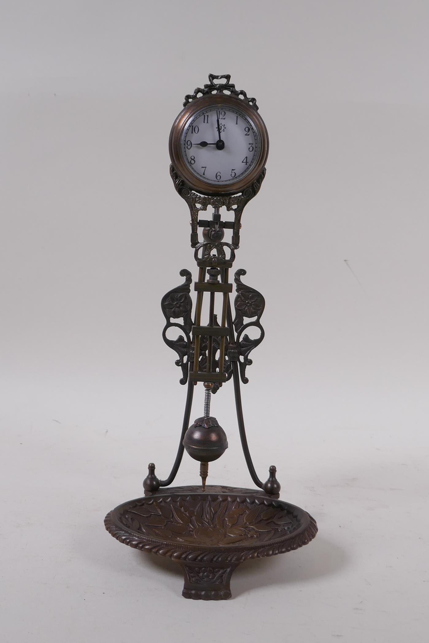 A bronzed metal mystery clock with a trinket dish base, 28cm high
