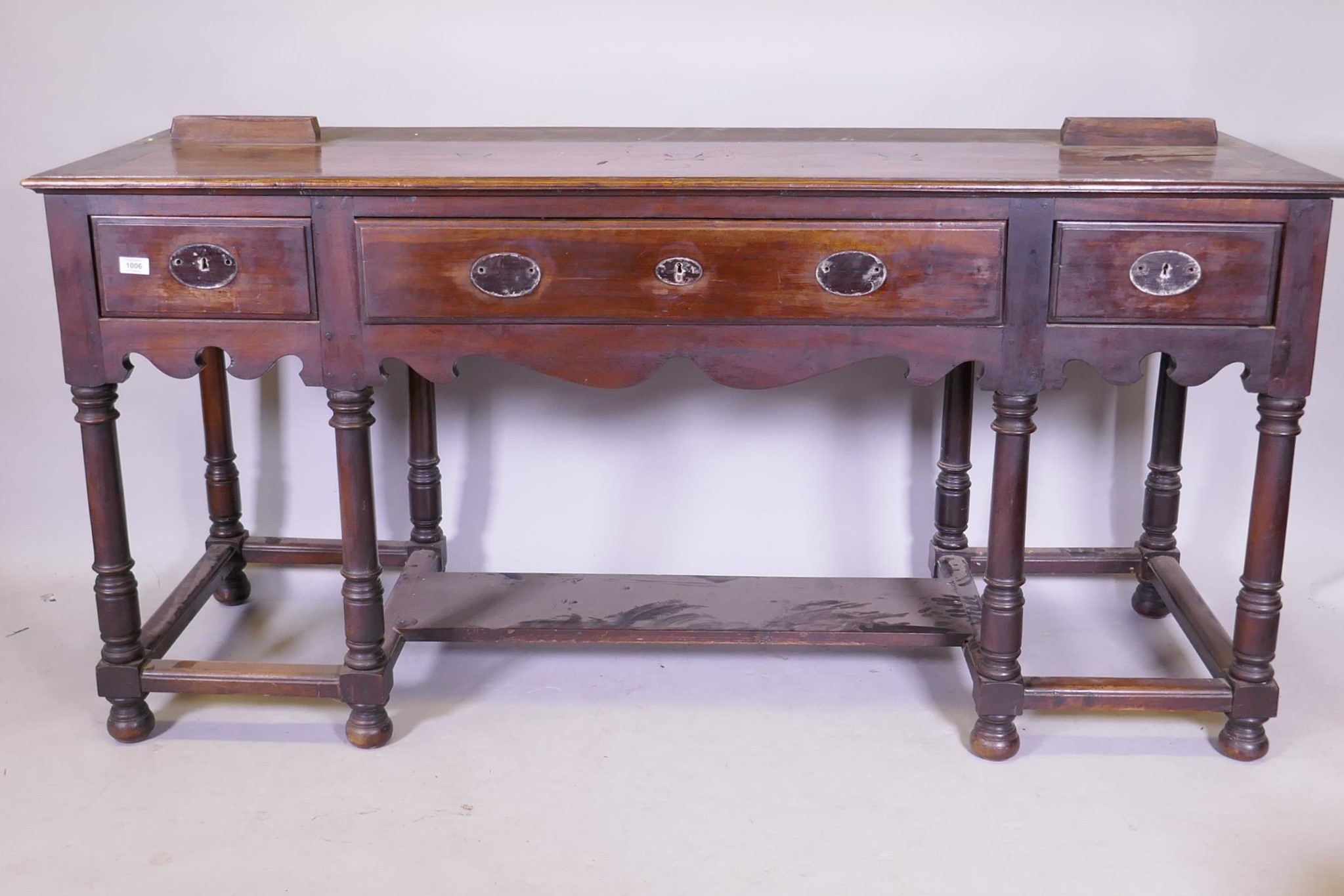 A South African hardwood Georgian style dresser base, with three drawers and shaped apron, raised on