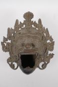 An antique Balinese bronze censer on tripod supports in the form of a garruda mask, 24cm x 28cm