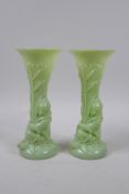 A pair of early C20th Art Nouveau milk glass spill vases in the form of a figure carrying bamboo,