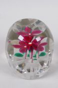 A facet cut glass paperweight decorated with a flower on a lattice base, signed in the flower