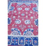 A Middle Eastern hand woven wool carpet with stylised floral designs on a faded red field, 320 x