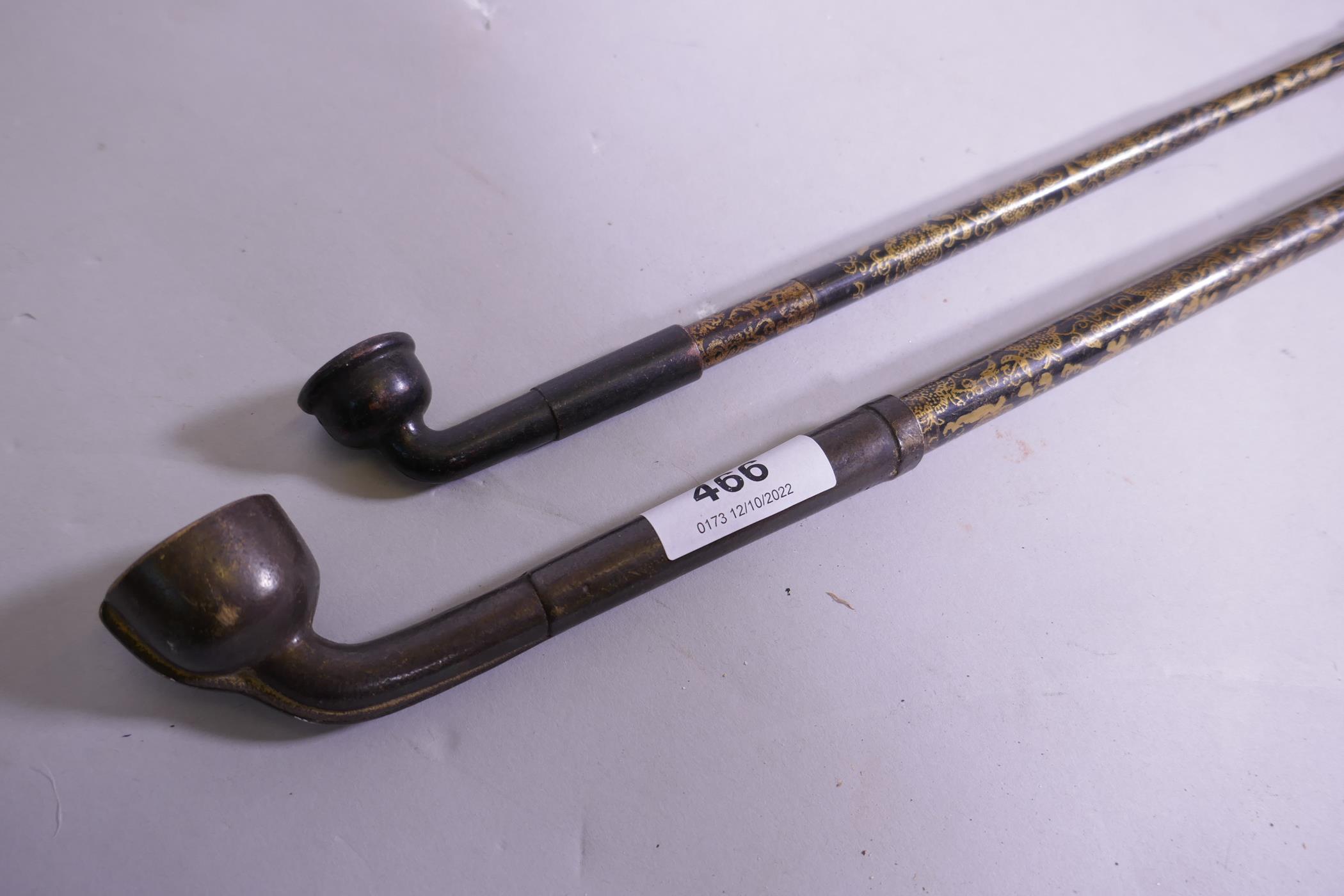 A Chinese opium pipe with gilt decorated shaft and another similar, 47cm long