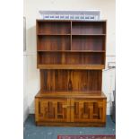 A rosewood veneered wall unit with tiered open shelves over a two door cupboard base by Troebs,