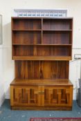 A rosewood veneered wall unit with tiered open shelves over a two door cupboard base by Troebs,