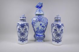 A pair of Delft jars with blue and white decoration and a larger jar and cover with parrot finial,