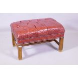 A buttoned leather foot stool, raised on moulded supports, 45 x 66 x 42cm