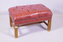 A buttoned leather foot stool, raised on moulded supports, 45 x 66 x 42cm