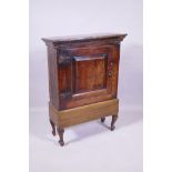 A C17th/C18th oak spice cupboard with single panelled door, fixed to a later base, 62 x 27 x 89cm