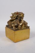 A Chinese polished brass seal with dragon knop set with stones, 9 x 9cm