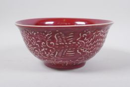 A Chinese red glazed porcelain bowl with raised dragon and phoenix decoration, Xuande 6 character