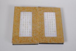 A Chinese wood and silk bound book containing white jade tablets with chased and gilt character