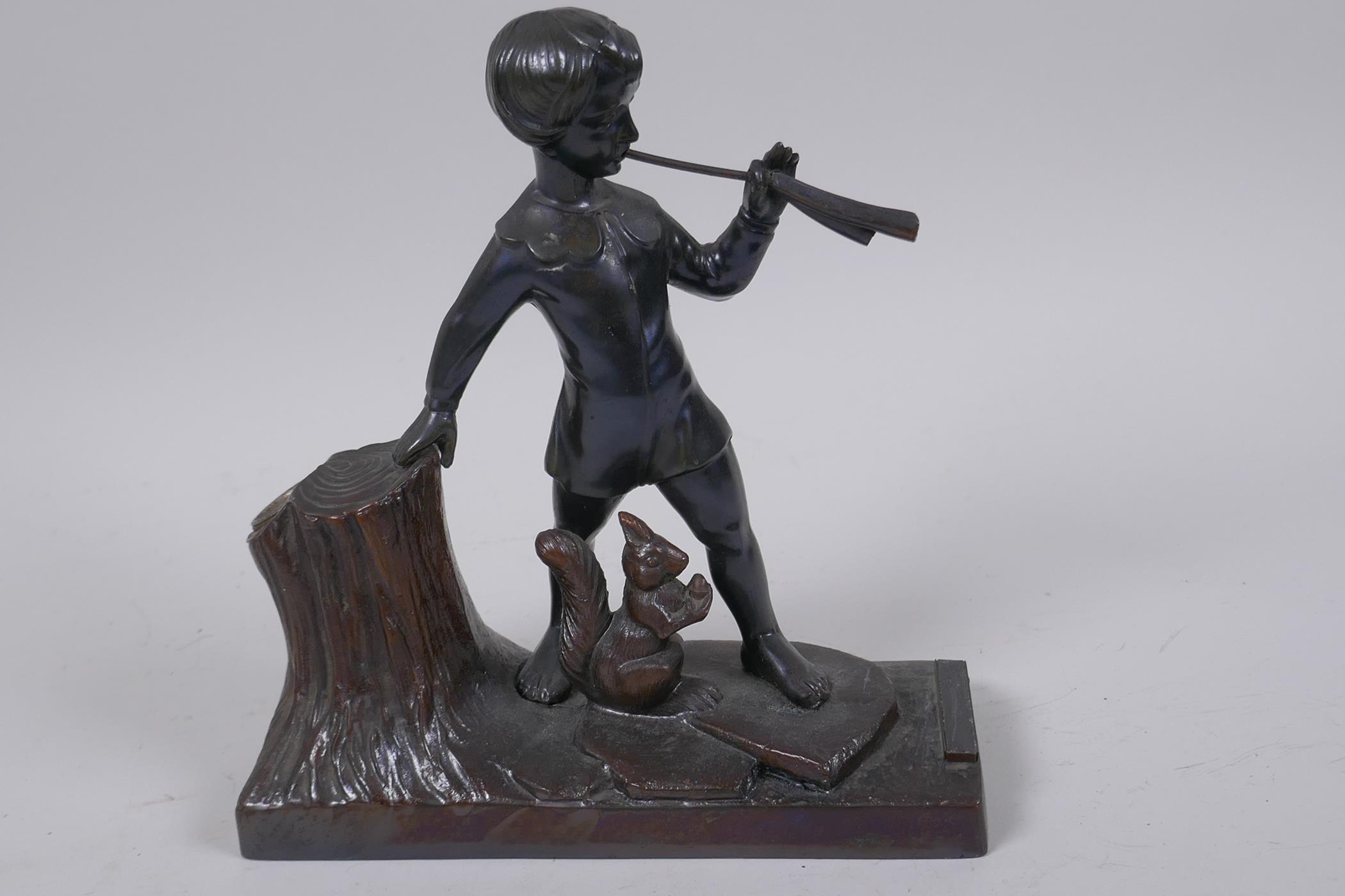 A spelter table top taper stand with striker, modelled as a boy piper and a squirrel, 17cm long