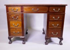A mahogany nine drawer pedestal desk with inset leather top and gadrooned edge, raised on cabriole