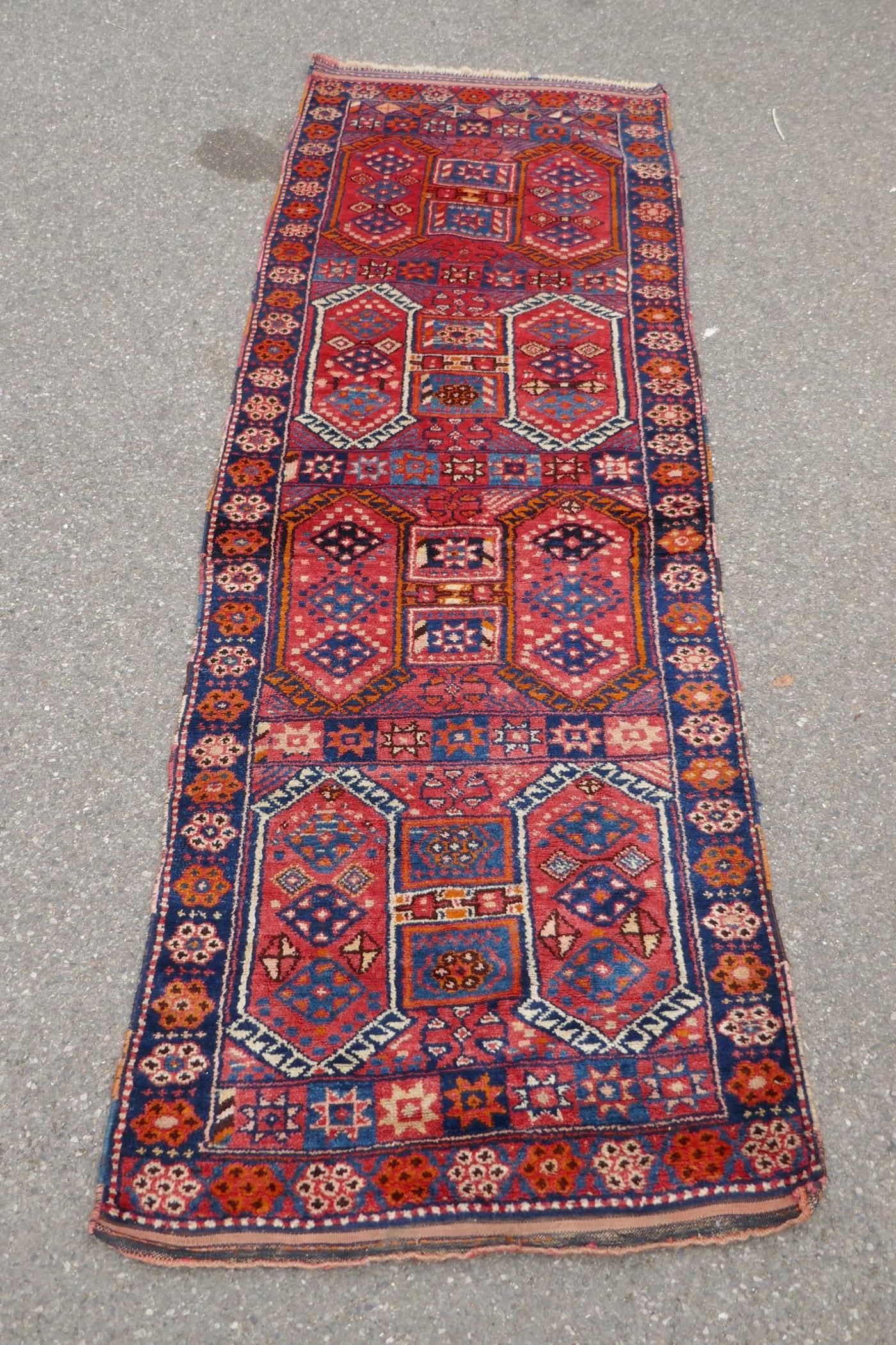 A Kurdish red ground full pile village rug/runner with unique geometric design, 290cm x 98cm
