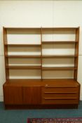 A mid century teak side cabinet with shelved upper section on a base of three drawers and two