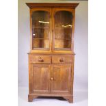 A C19th oak bookcase, the upper section with arched glazed doors and moulded decoration over a