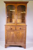 A C19th oak bookcase, the upper section with arched glazed doors and moulded decoration over a
