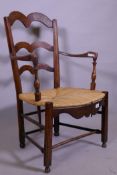 An early C19th French fruitwood armchair with shaped back and crook arms, rush seat and shaped