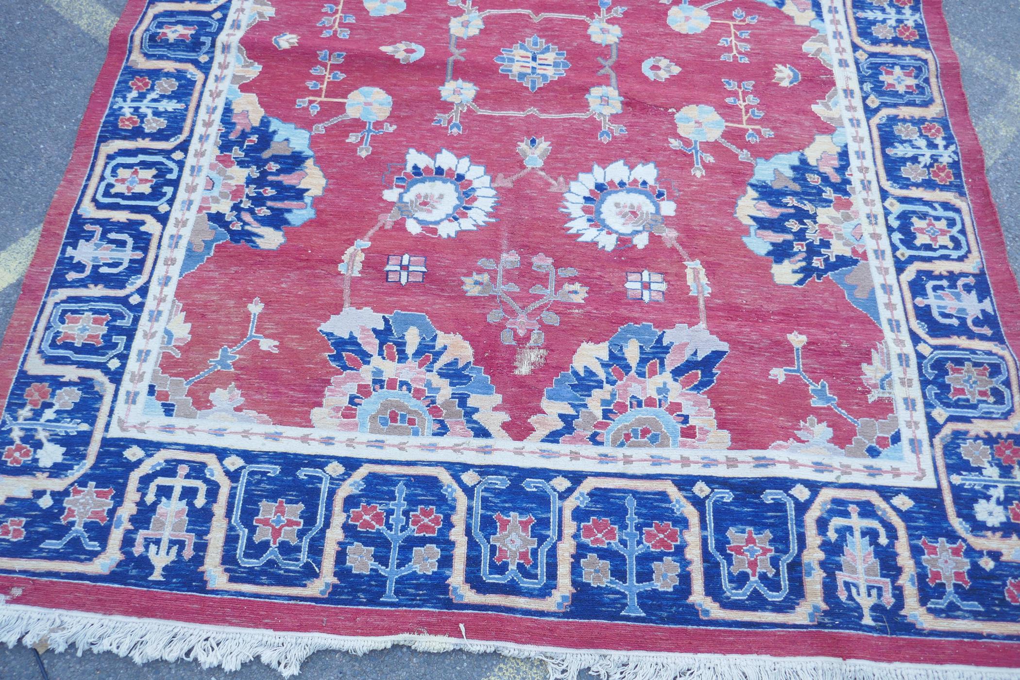 A Middle Eastern hand woven wool carpet with stylised floral designs on a faded red field, 320 x - Image 2 of 9