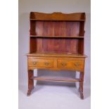 A C19th oak Arts & Crafts dresser, the upper section with shelves, the base with two drawers over