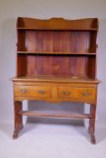 A C19th oak Arts & Crafts dresser, the upper section with shelves, the base with two drawers over